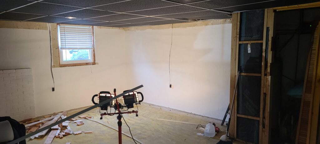 A basement undergoing restoration with new white walls and exposed studs after water damage remediation by 1d Remedy LLC in Mechanicsburg, PA