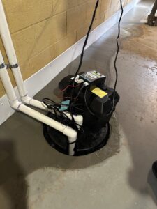 A basement sump pump installation with water on the floor by EverDry Toledo in Toledo, OH.