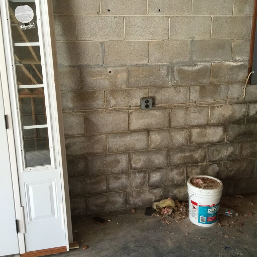 A basement wall showing visible water stains and efflorescence, indicating water damage, before repair by Stay Dry Waterproofing LLC in Marysville, OH.