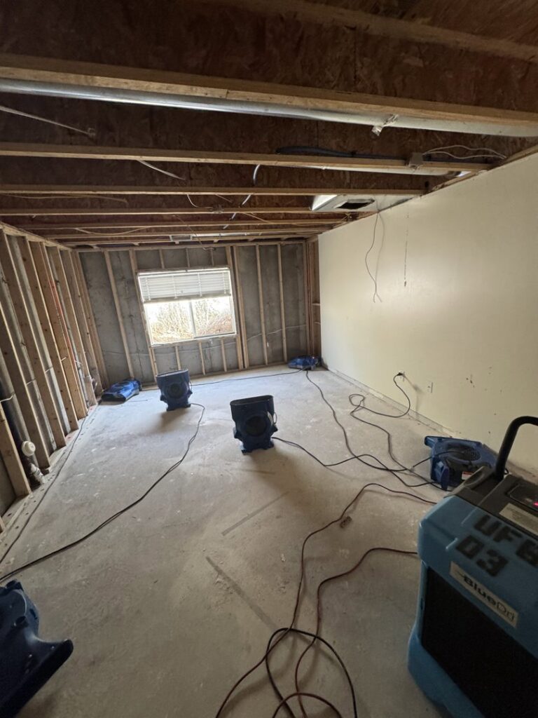 A basement undergoing extensive water damage demolition and drying with multiple air movers by Utah Flood Guys in Sandy, UT.