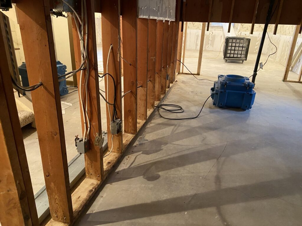 A basement undergoing water damage drying with professional equipment and exposed framing by Anytime Flood Restoration in Thornton, CO