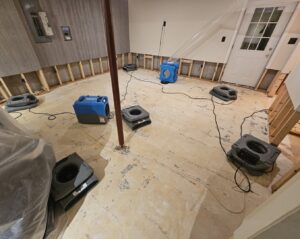 A basement undergoing water damage restoration with exposed studs and drying equipment from Remont Restoration in Hagerstown, MD.