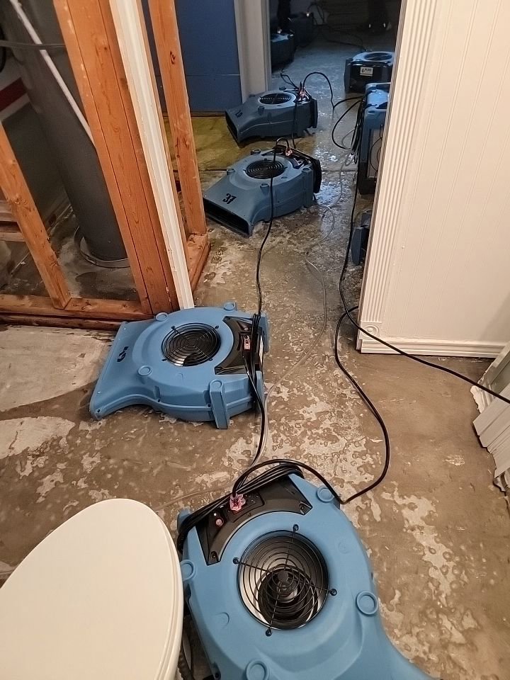 Multiple air movers drying a concrete basement floor affected by water damage by Pure Restore in Northglenn, CO.