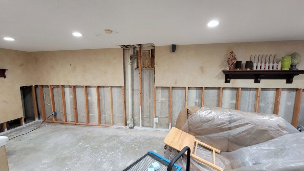 A basement room with drywall removed, revealing water damage and exposed wall studs during remediation by Utah Disaster Team in Layton, UT.