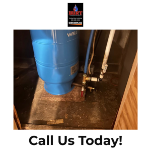 A basement floor showing signs of water damage and a well tank, serviced by Burt Mechanical in Flint, MI.
