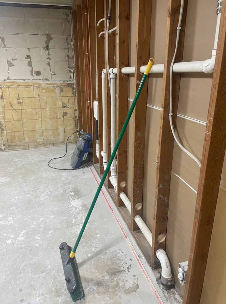 A basement undergoing water damage restoration with exposed studs and drying equipment from USA Water Damage Thunder Restoration in Coon Rapids, MN.