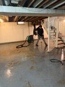 A water damage specialist performing water extraction in a flooded basement using professional equipment for H2O Pros Water Restoration Services in Westland, MI.