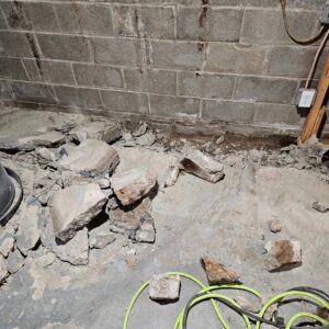 Concrete debris on a basement floor, showing preparation for waterproofing by EverDry Toledo in Toledo, OH.