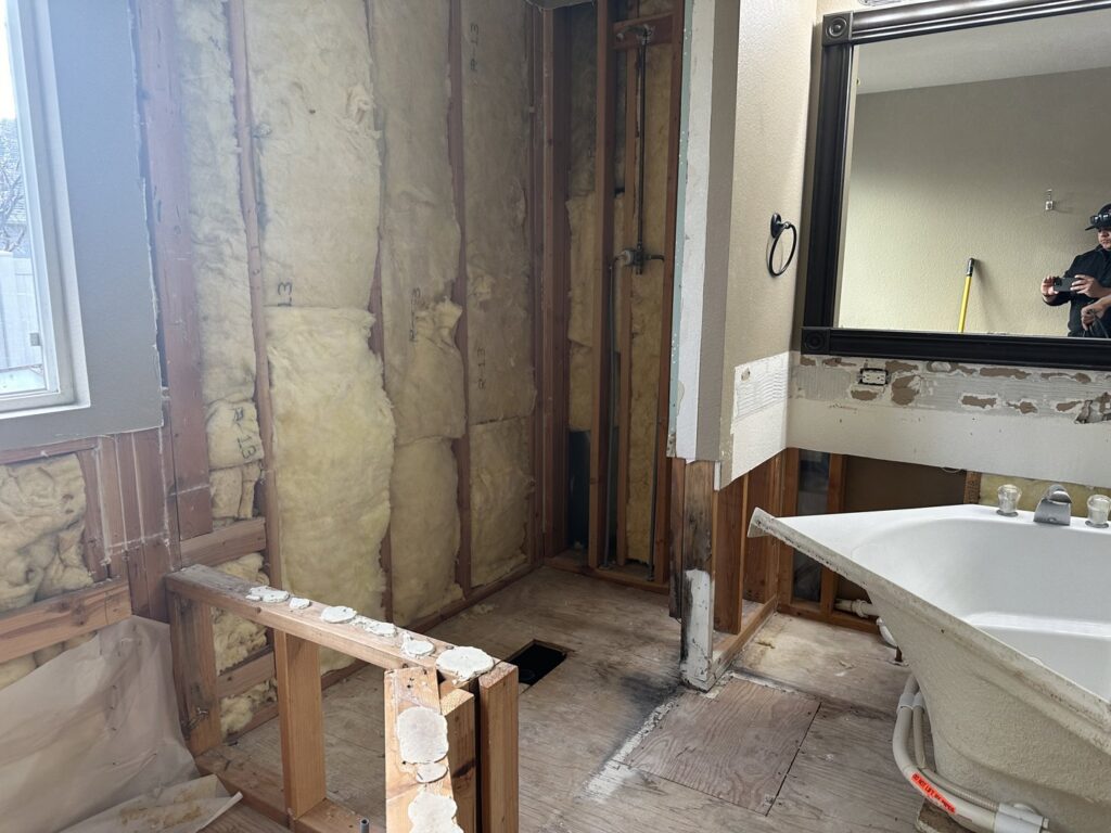A bathroom undergoing demolition with exposed insulation for water damage repair by Restorex in Petaluma, CA.