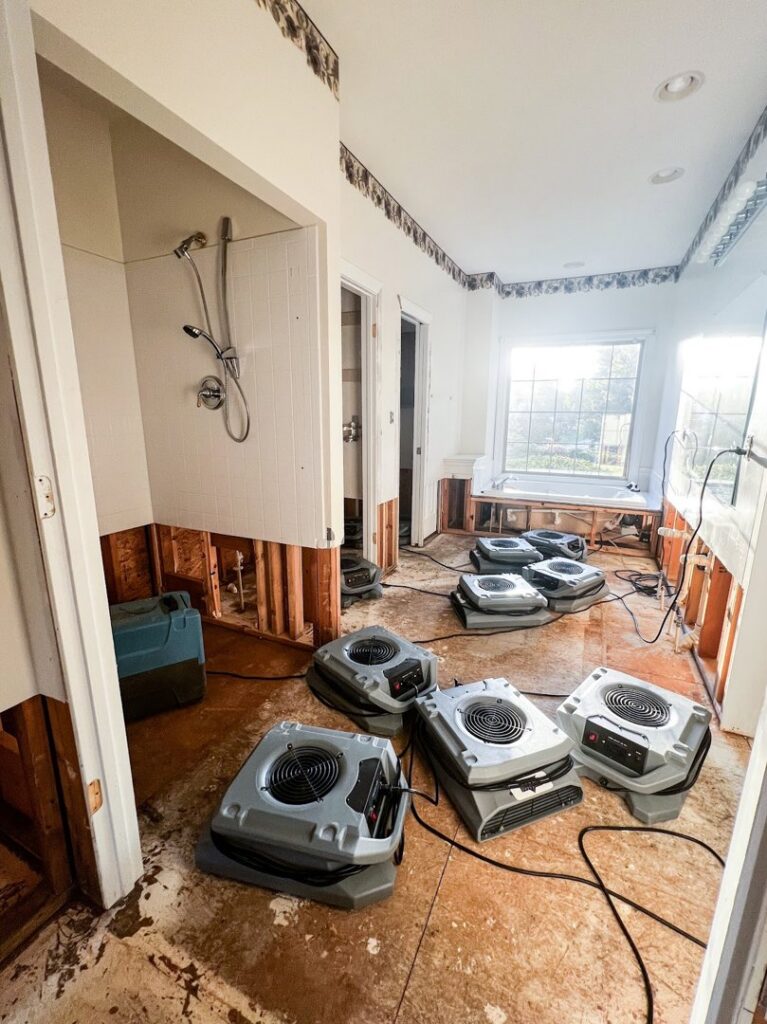 A bathroom with exposed framing and multiple drying machines for water damage cleanup by Remont Restoration in Hagerstown, MD.