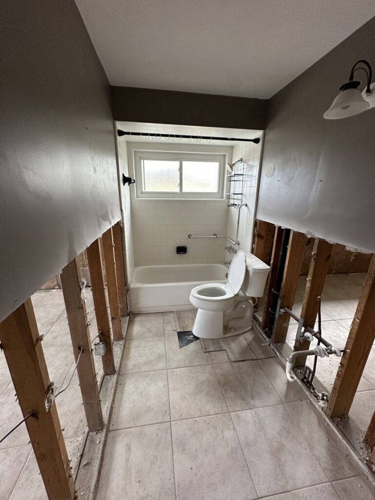 A bathroom with lower drywall removed, exposing studs for water damage remediation by Catalyst Restoration in Hagerstown, MD.