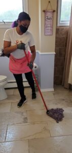 A house cleaner mopping a bathroom floor with a red mop for TAG Team Cleaning of West Hartford, CT