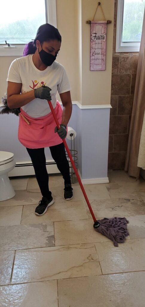 A house cleaner mopping a bathroom floor with a red mop for TAG Team Cleaning of West Hartford, CT