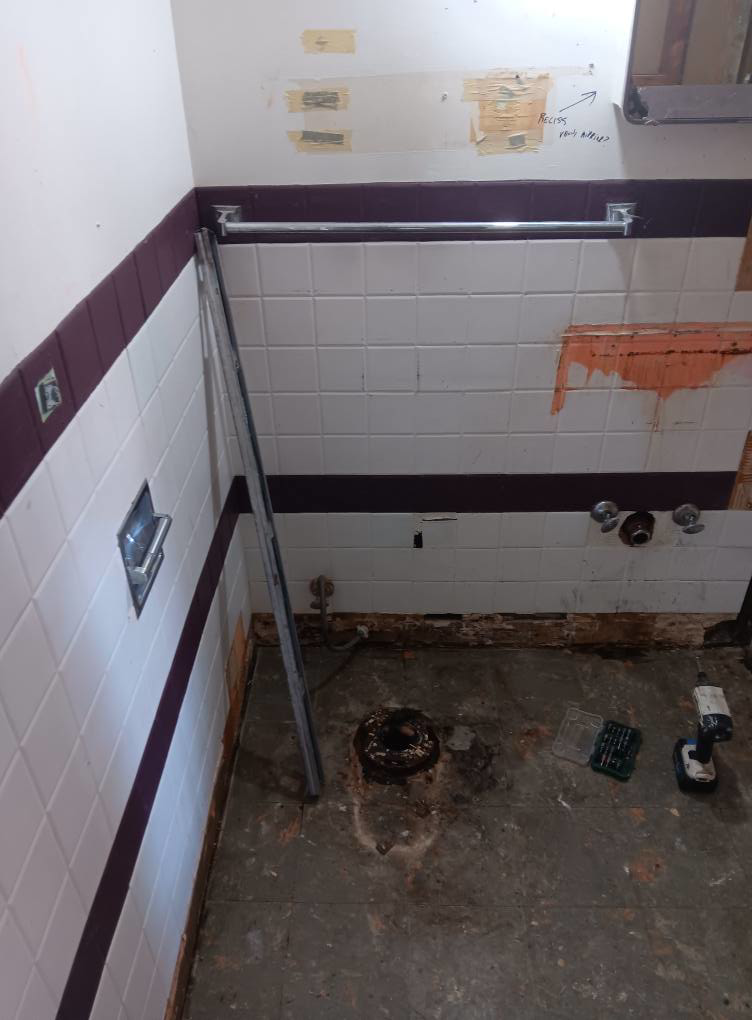 Bathroom floor tile removal exposing subfloor for water damage repair by Integrity Solutions in Omaha, NE.