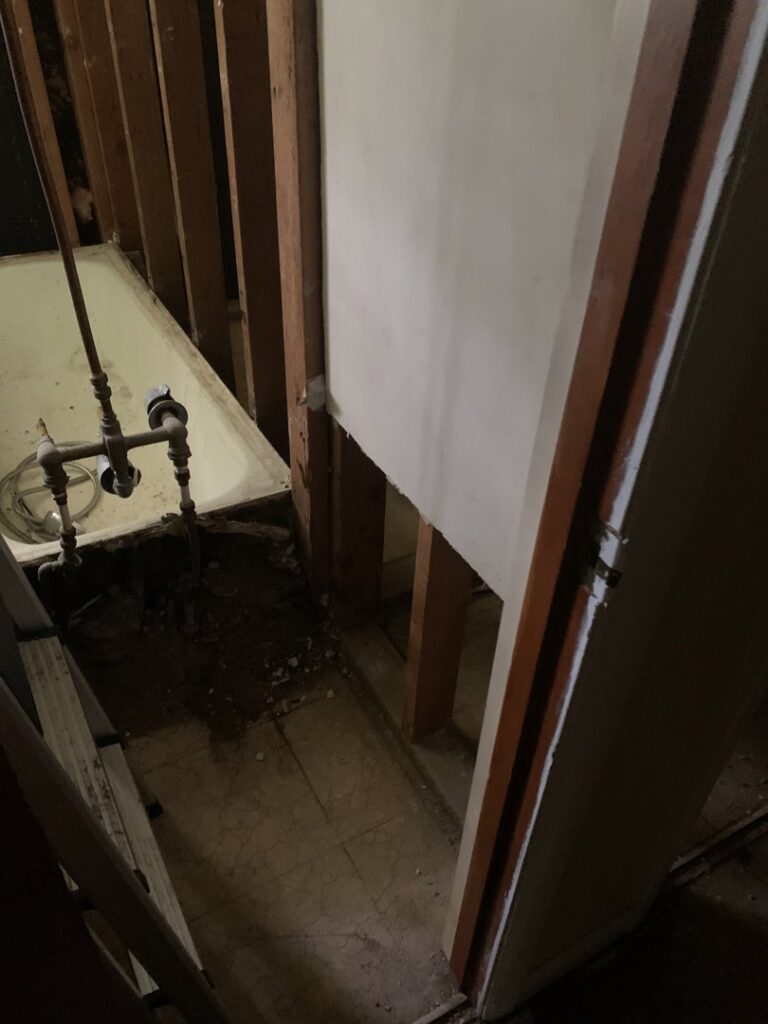 An interior bathroom undergoing demolition, showing exposed pipes and partially removed walls by HaysCo Facilities Management, Inc. in Dothan, AL.