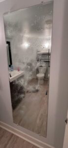A bathroom mirror being cleaned with solution, demonstrating a house cleaning task in progress by Nichelle's touch housekeeping LLC in Detroit, MI.