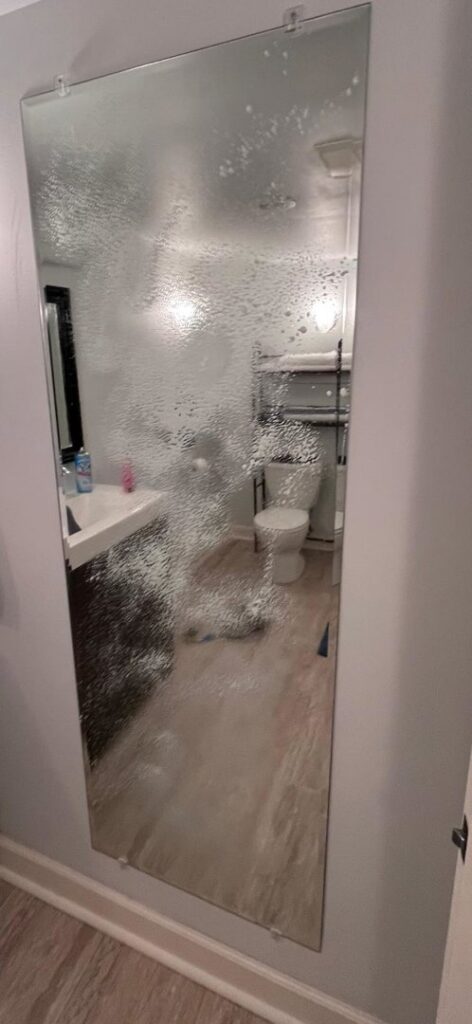 A bathroom mirror being cleaned with solution, demonstrating a house cleaning task in progress by Nichelle's touch housekeeping LLC in Detroit, MI.