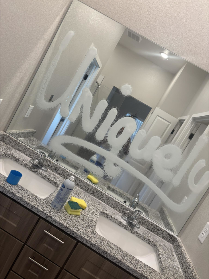 A bathroom mirror being cleaned with cleaning supplies on the counter by Uniquely Clean Professional Services in Kansas City, MO.