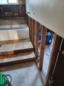 A bathroom under restoration with exposed studs, a new bathtub, and a blue dehumidifier for drying by A1 Restoration of Spokane in Post Falls, ID.