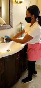 A house cleaner cleaning a bathroom sink and faucet for TAG Team Cleaning of West Hartford, CT