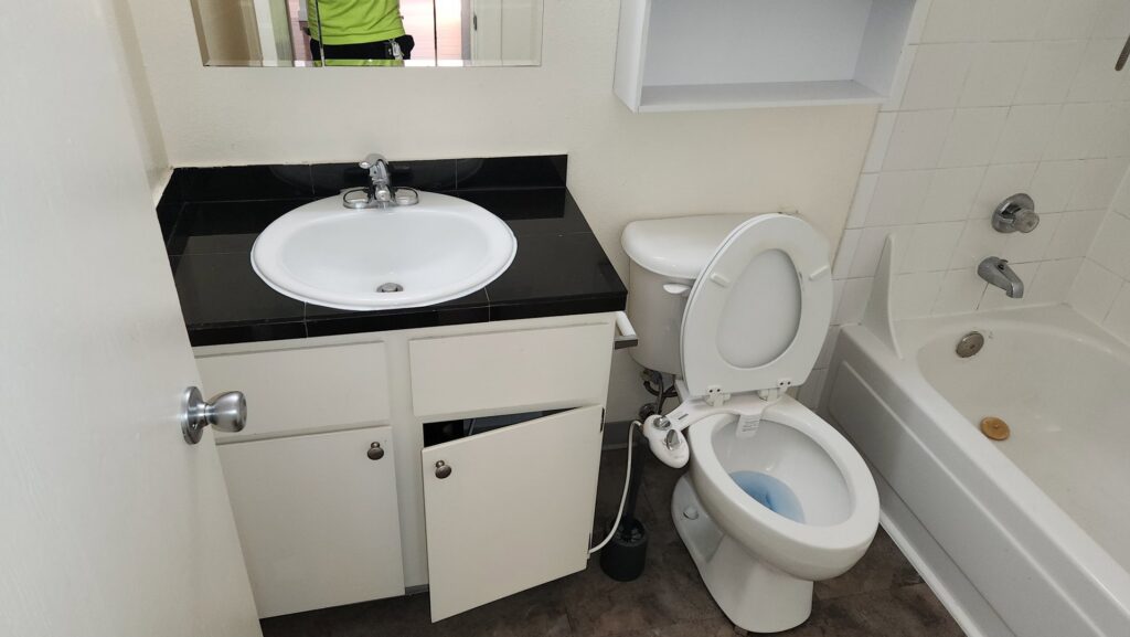 A residential bathroom with a sink, toilet, and tub, appearing ready for or in the process of cleaning by Eyedeal Cleaning Services in Gresham, OR.