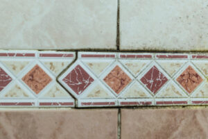 Close-up of bathroom tiles with black mold and mildew in the grout lines, indicating moisture issues addressed by Local Clean Up Specialists in Green Bay, WI.