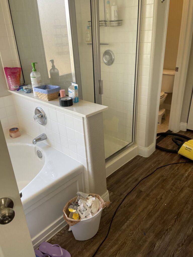 A bathroom with a clean tub and shower, with a vacuum cleaner on the floor, by Picky Performance Cleaning in North Las Vegas, NV