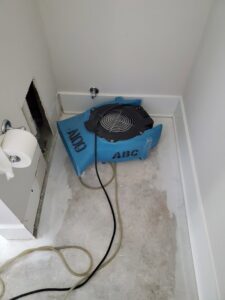 Water damage drying equipment, including an air mover, in a bathroom by ABC Cleaning and Restoration in Harvest, AL.