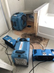 Water damage drying equipment in a bathroom with exposed subfloor and visible damage by Restoration 1 of Birmingham in Pelham, AL.