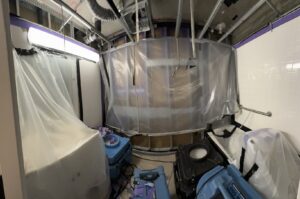 A bathroom undergoing water damage restoration with plastic containment and multiple drying machines by Island Restoration LLC in Kapolei, HI.