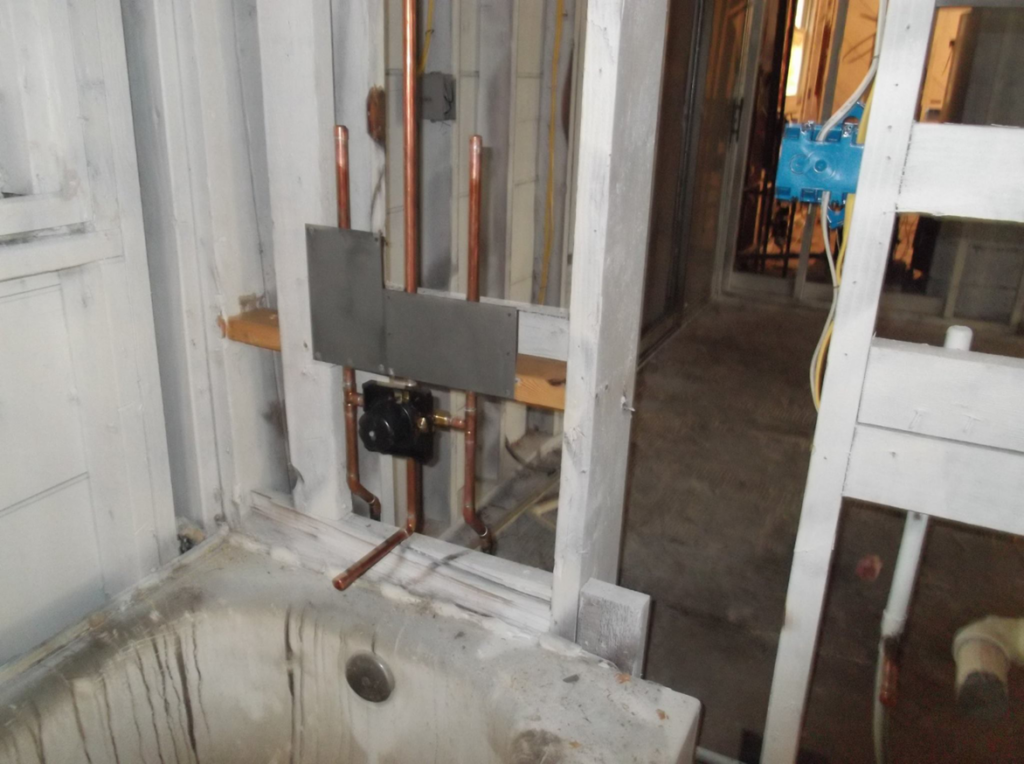 Exposed plumbing and framing in a bathroom during water damage restoration by Rapid Recovery Service, Inc. in Warren, MI.