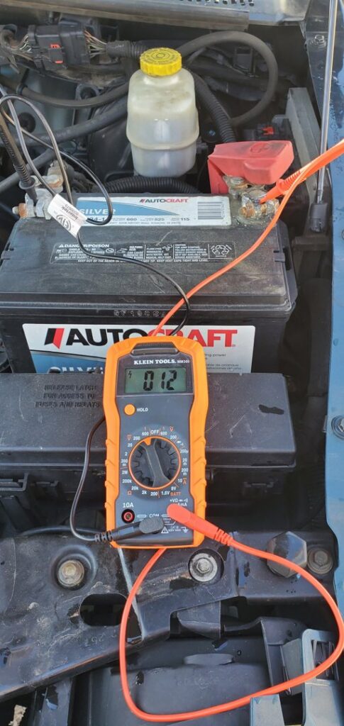 A multimeter connected to a car battery for a diagnostic test by Liberty Auto Rescue in Colorado Springs, CO.