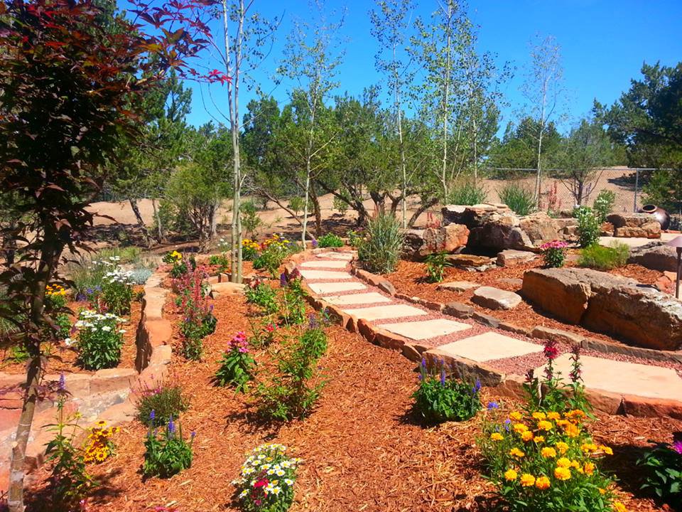 A beautiful landscaped garden with a winding stone pathway and vibrant flowers by Pro Scape in Eustis, FL.