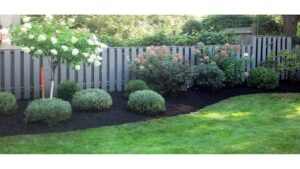 A beautifully landscaped backyard with green grass and mulched garden beds, showcasing work by Love it Lawn Care in Butte, MT