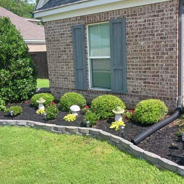 A beautifully landscaped garden bed with fresh mulch and neatly trimmed shrubs by Day One Landscaping in Mississippi.