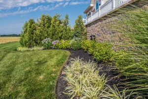 A beautifully maintained green lawn with vibrant landscaped beds at a residential property by Bailey's Lawn and Landscape in Smyrna, DE.