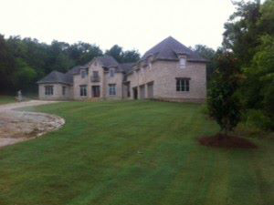 A beautifully maintained green lawn in front of a large house by Scruggs Lawn Care Inc. in Tupelo, MS.