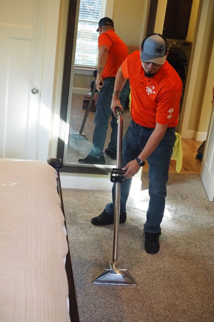 A house cleaner from Idaho Gem Cleaning performing professional carpet cleaning in a bedroom in Caldwell, ID.
