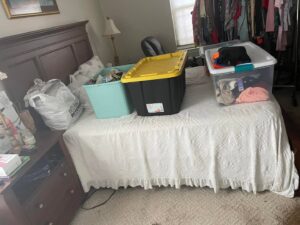 A bedroom with storage bins on the bed, illustrating a decluttering and organizing service by Skedaddle Cleaning Services in Eufaula, AL.