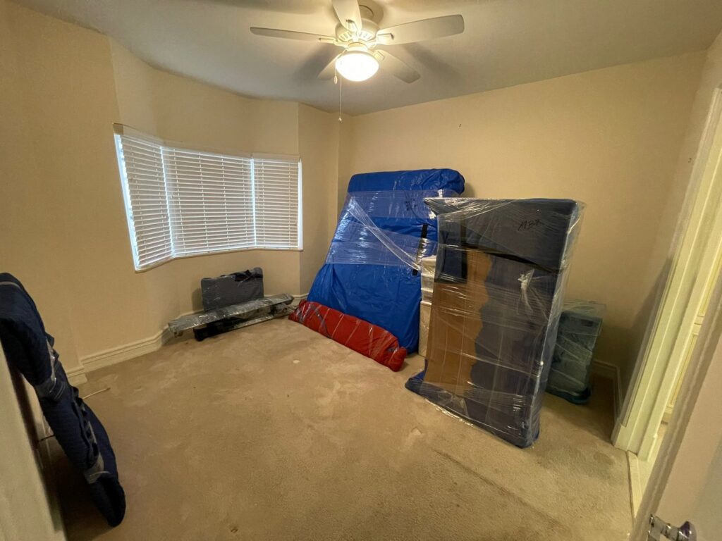 A bedroom with furniture and items carefully wrapped and prepared for moving by Orellana AV Moving in Miami, FL.