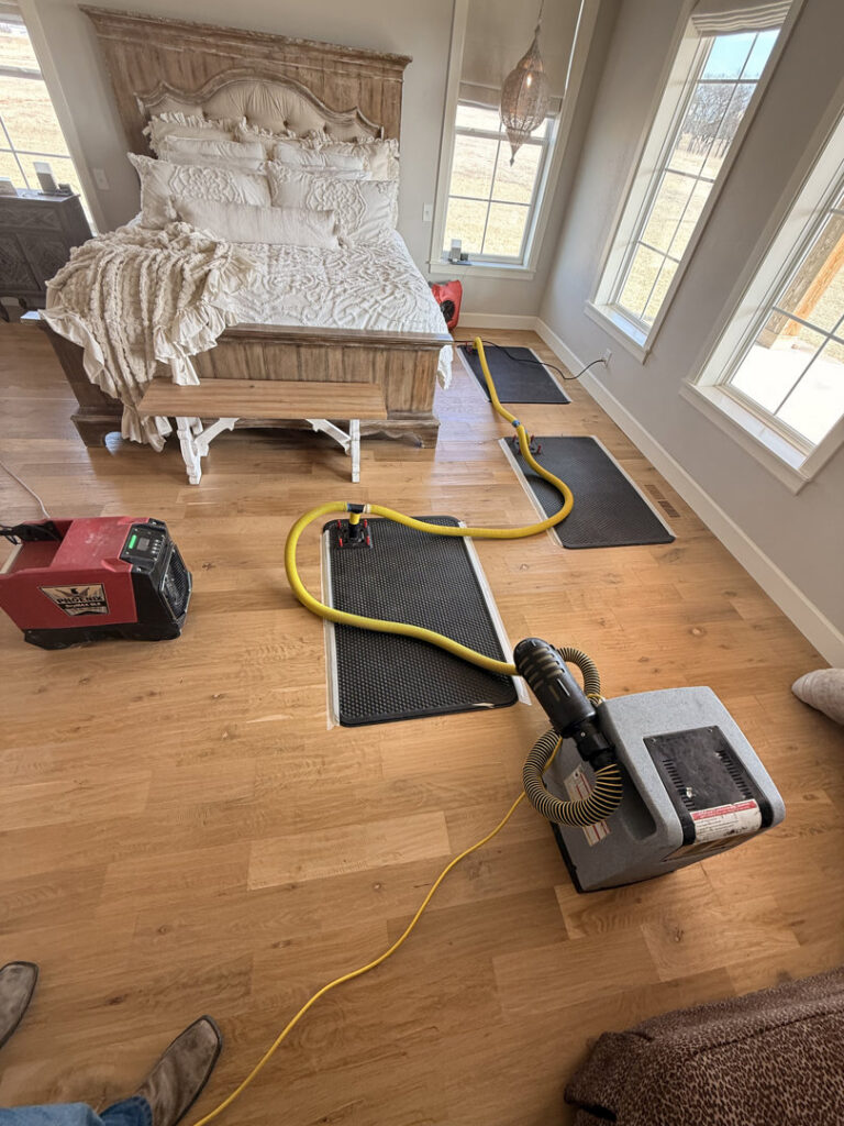 Water damage drying equipment, including air movers and dehumidifiers, set up in a bedroom by Paul Davis of Norman & SW OKC in Norman, OK.