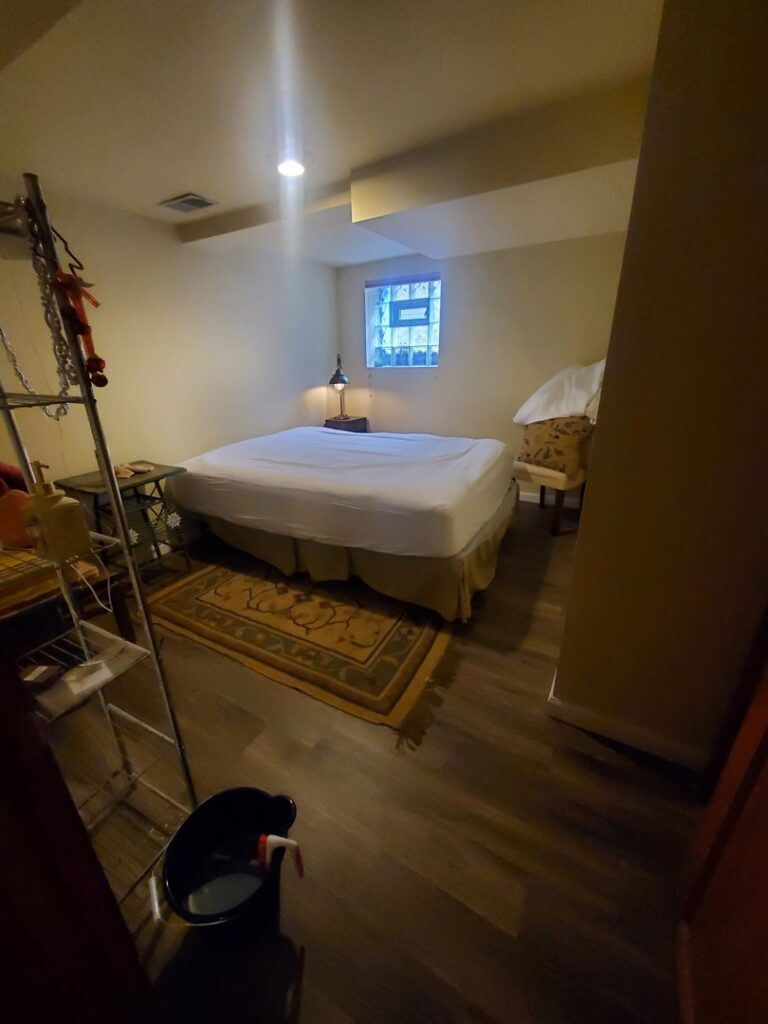 A bedroom with a cleaning bucket on the floor, indicating a house cleaning service by Chelle's Cleaning Services in Gary, IN.