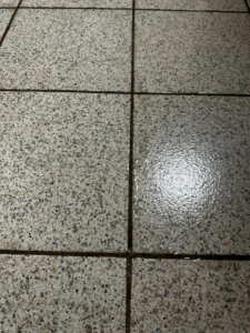 A clear before and after comparison of speckled tile floor cleaning by Dust Devil Cleaning in Eugene, OR.