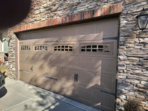 A beige garage door with windows and decorative hardware installed by Doors & more,inc in Quincy, IL