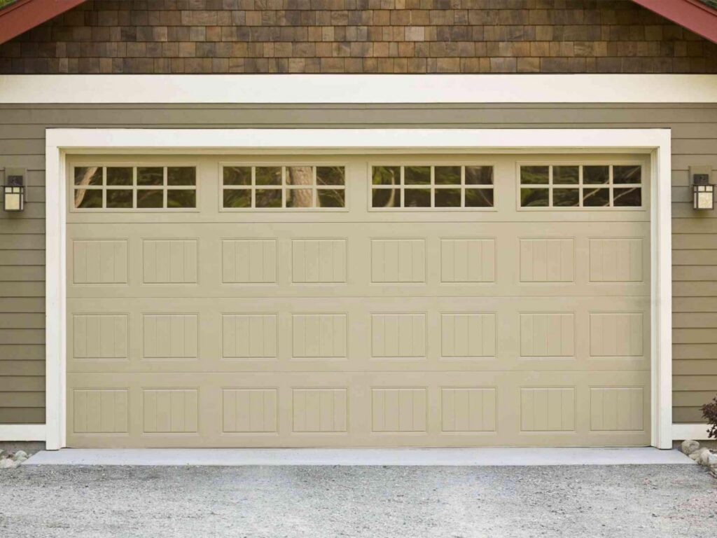 A beige garage door with top windows installed on a residential house by Up & Down Garage Doors in Bridgeport, CT.
