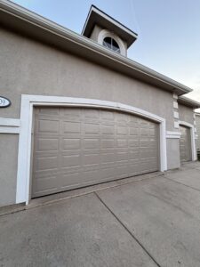 A newly installed beige panel garage door with an arched top by The Door Pros in Wichita, KS
