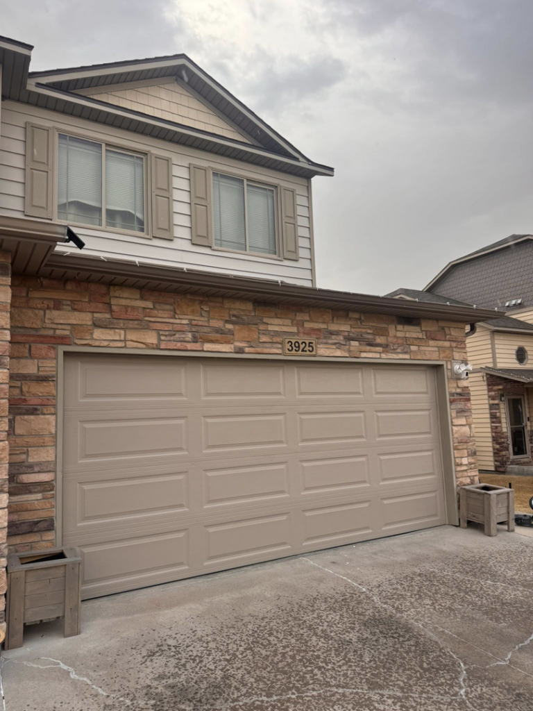 A beige paneled residential garage door installed by Cowboy State Garage Doors, LLC in Cheyenne, WY.
