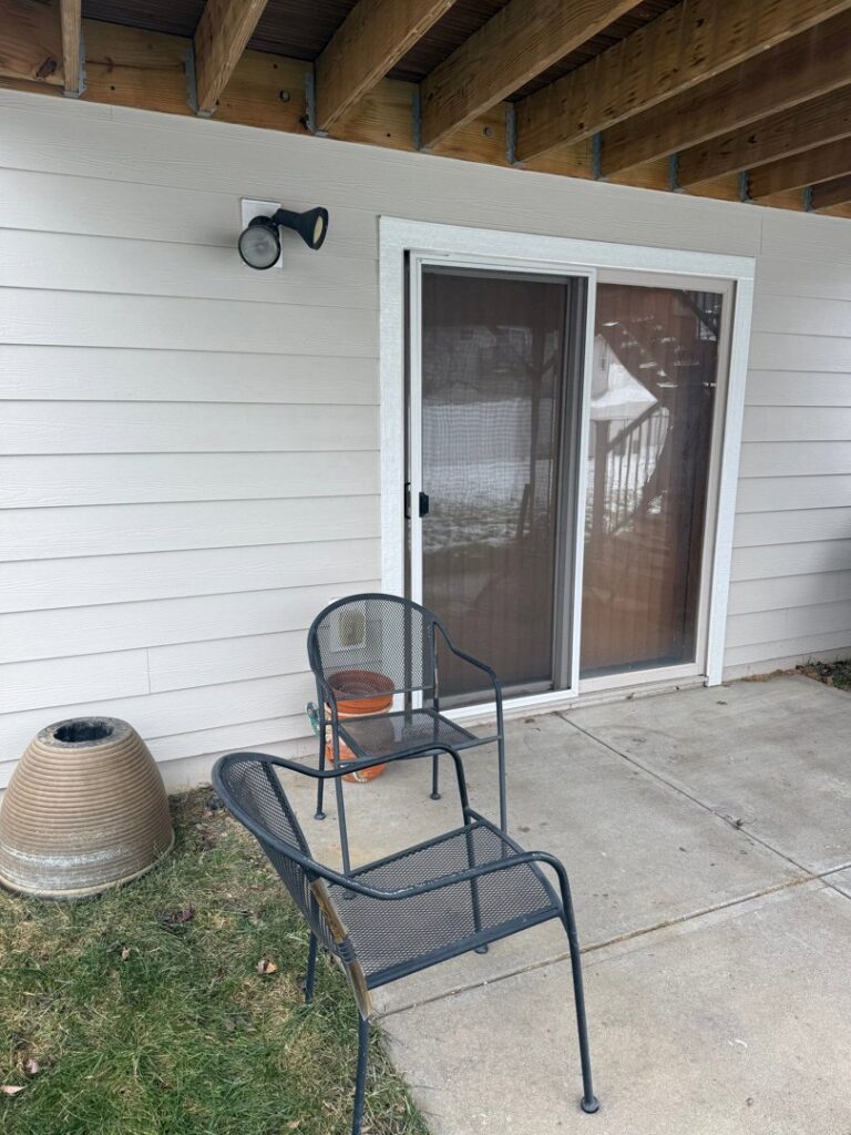 Newly installed light beige siding visible next to a sliding patio door, completed by Bishop Exteriors in Omaha, NE.