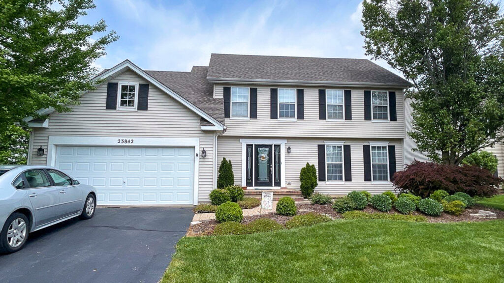 A beautiful home with light beige vinyl siding and black shutters, completed by Legend Exteriors & Construction in West Chicago, IL