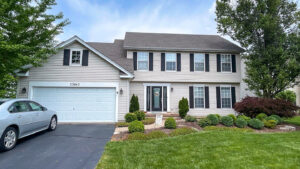 A beautiful home with light beige vinyl siding and black shutters, completed by Legend Exteriors & Construction in West Chicago, IL